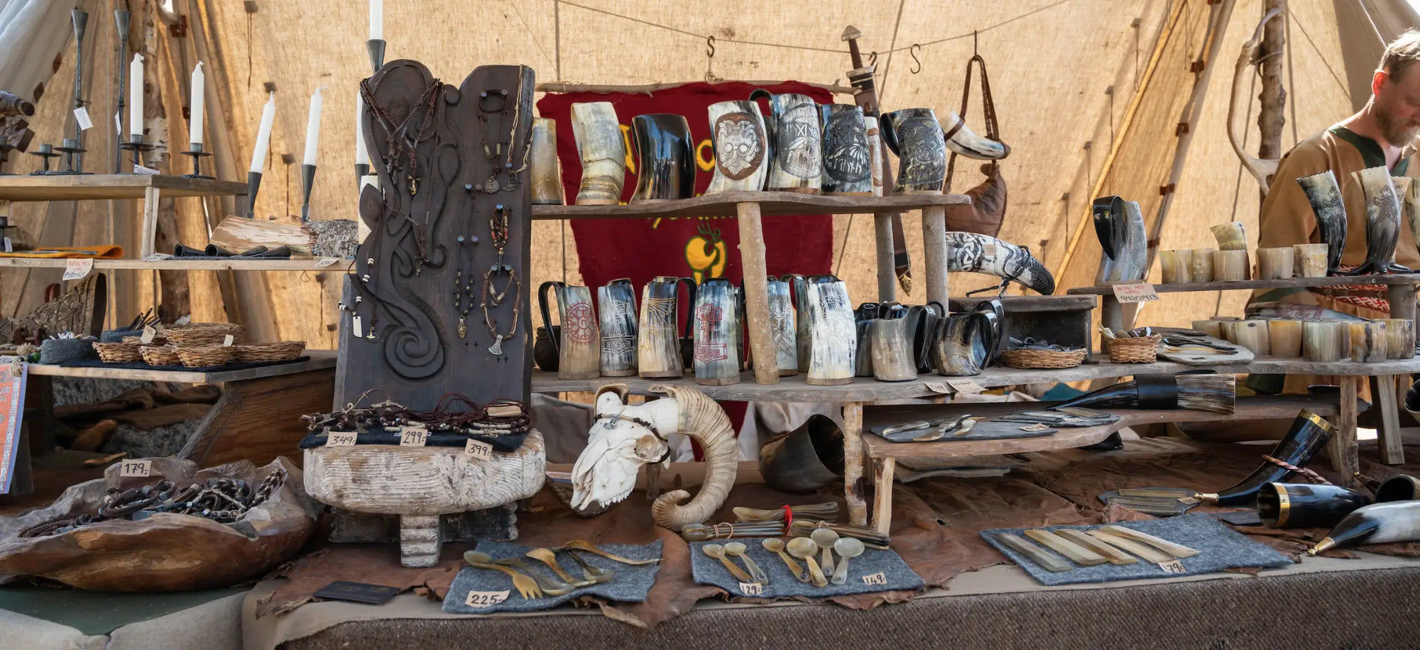 A display of Viking objects on a table, including cups, horns, candles and ancient Norse jewelry