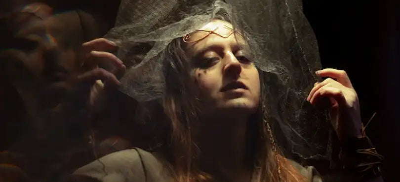 A woman prepares for a Viking-style wedding, with a lightweight fabric being held over her head. Viking wedding rings formed a big part of ceremonies like this one 