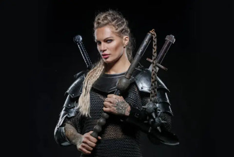 A modern day Viking woman stands holding two ancient weapons